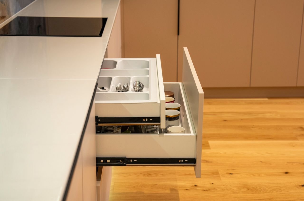 Open kitchen drawer with organized cutlery divider in a modern kitchen setting showcasing functionality and design.